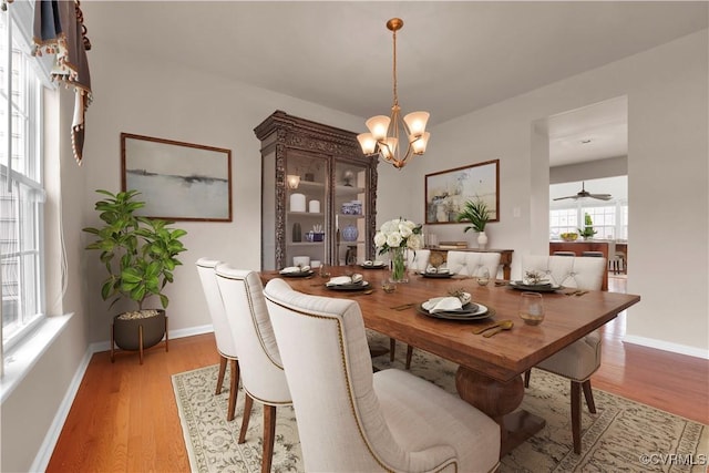 dining area with a chandelier, baseboards, light wood-type flooring, and a ceiling fan