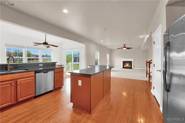 kitchen featuring appliances with stainless steel finishes, a ceiling fan, a sink, a glass covered fireplace, and recessed lighting