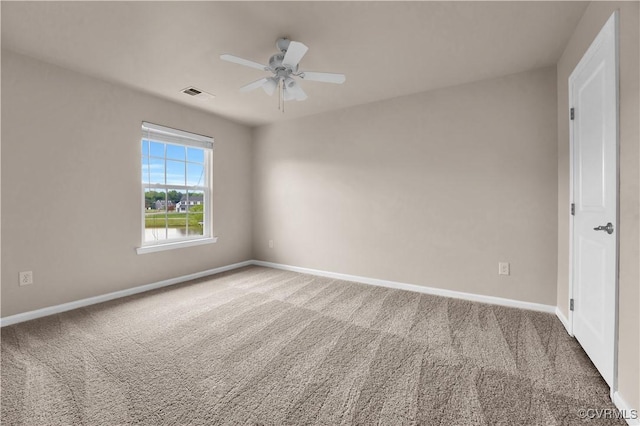 carpeted spare room featuring baseboards and ceiling fan