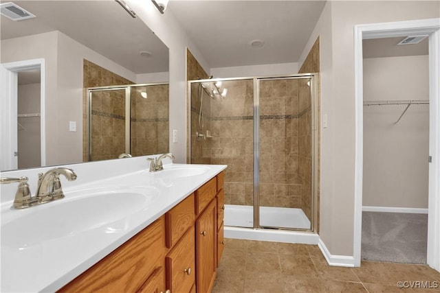 bathroom featuring a shower stall, baseboards, tile patterned flooring, and a walk in closet