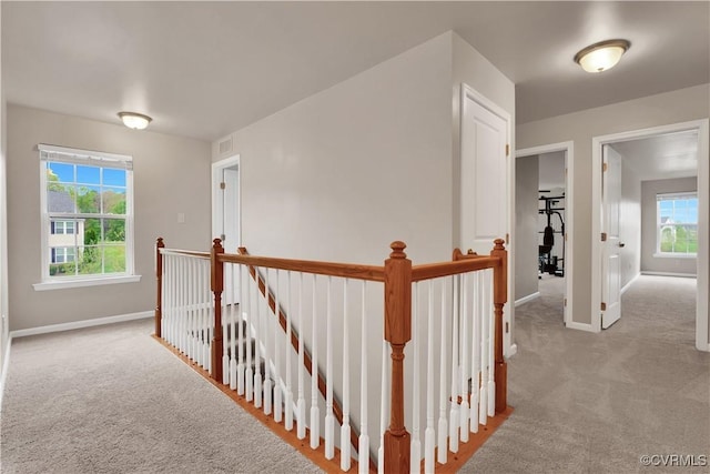 hallway featuring an upstairs landing, carpet, and baseboards