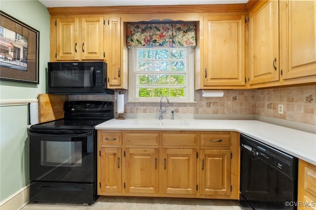 kitchen with a sink, light countertops, decorative backsplash, and black appliances