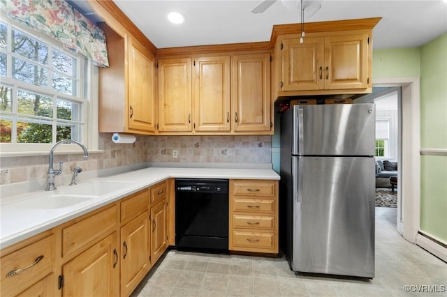 kitchen with tasteful backsplash, a sink, light countertops, freestanding refrigerator, and black dishwasher