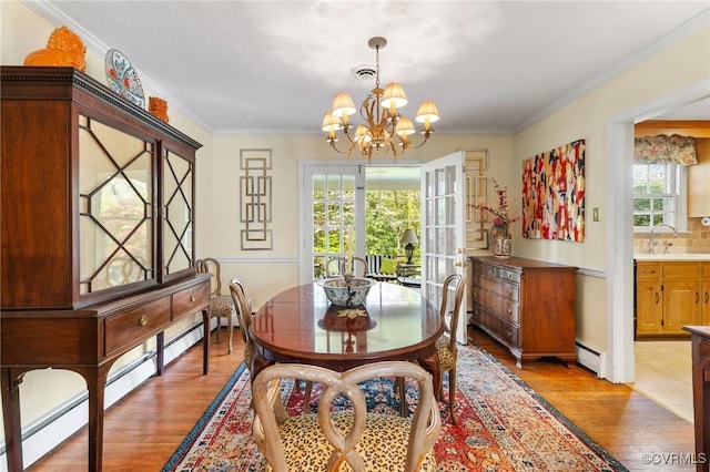 dining space with light wood-style floors, baseboard heating, a wealth of natural light, and an inviting chandelier