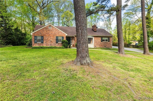ranch-style home featuring brick siding, a front yard, and a chimney
