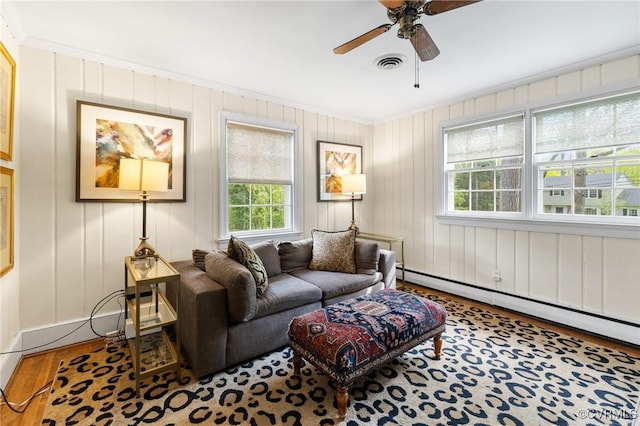 living room with a baseboard radiator, a ceiling fan, visible vents, and a wealth of natural light