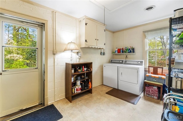 clothes washing area featuring cabinet space, visible vents, washing machine and dryer, and a wealth of natural light