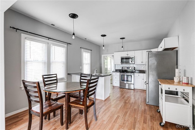 dining area featuring visible vents, light wood finished floors, and baseboards
