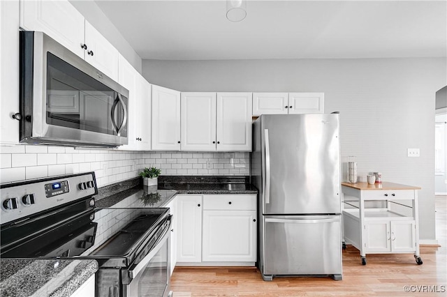 kitchen with white cabinets, appliances with stainless steel finishes, light wood-style flooring, and tasteful backsplash