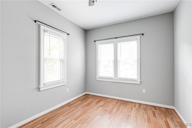 unfurnished room featuring a healthy amount of sunlight, baseboards, light wood-style flooring, and visible vents