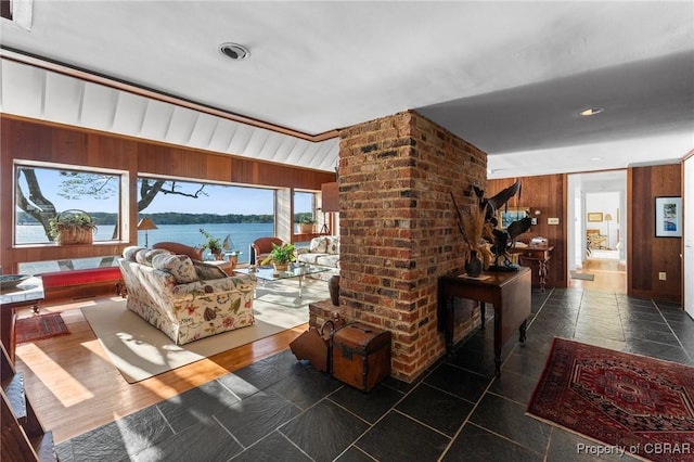 living area with visible vents, wooden walls, and a water view