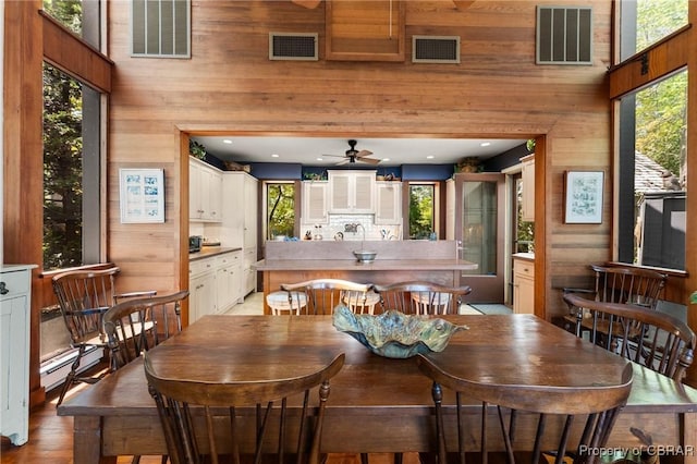 dining space with visible vents, wood walls, and a healthy amount of sunlight