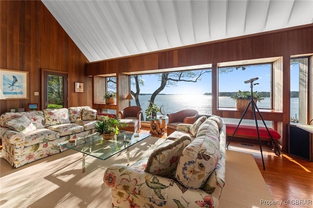 living area with wooden walls, wood finished floors, vaulted ceiling, and a water view