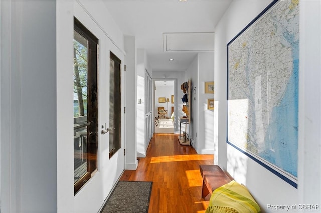 corridor with attic access, french doors, and wood finished floors