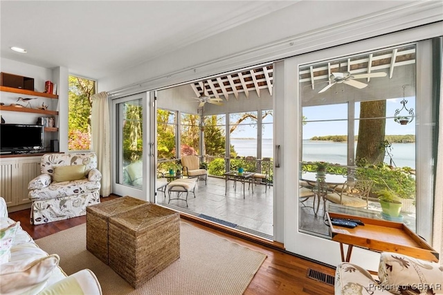 doorway to outside with wood finished floors, visible vents, a ceiling fan, and a water view