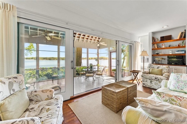 sunroom / solarium featuring wood finished floors and a water view