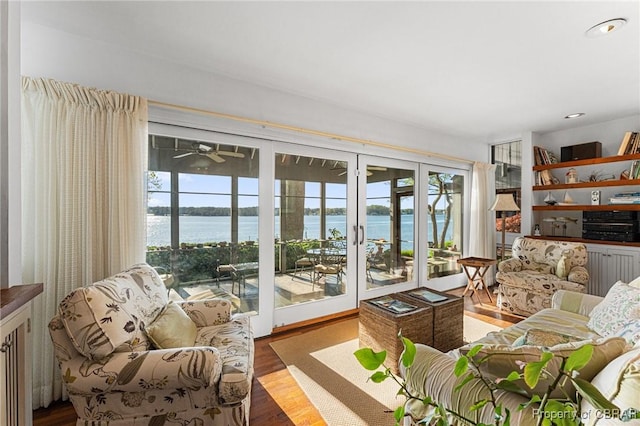 living area with plenty of natural light, wood finished floors, recessed lighting, and a water view