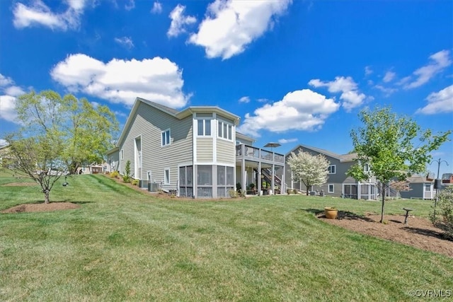 rear view of house featuring a lawn and stairs