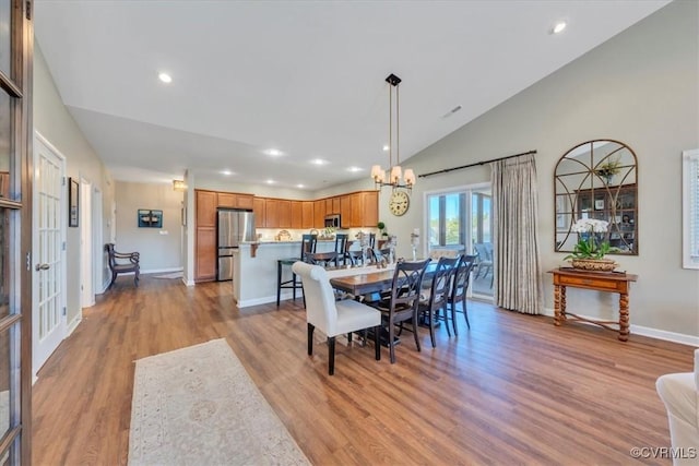 dining space featuring an inviting chandelier, vaulted ceiling, baseboards, light wood-style floors, and recessed lighting