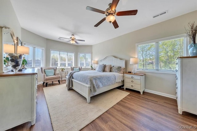 bedroom with baseboards, visible vents, multiple windows, and wood finished floors