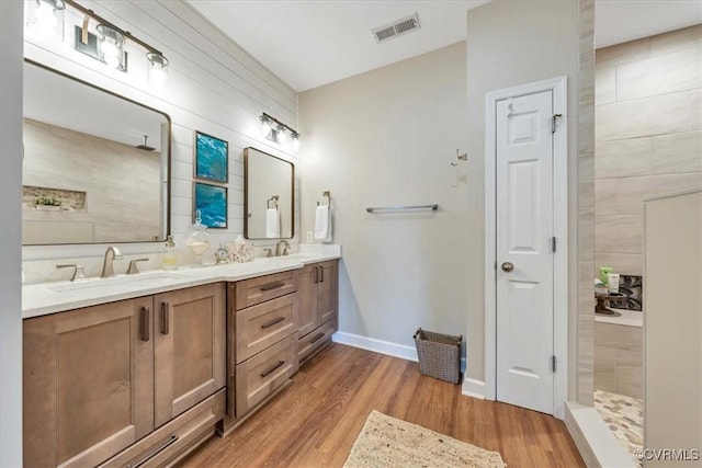 bathroom featuring a walk in shower, a sink, visible vents, and wood finished floors