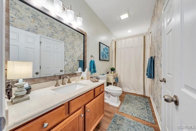 bathroom with toilet, curtained shower, wood finished floors, and vanity