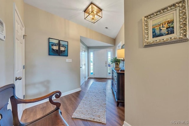 foyer entrance featuring baseboards, visible vents, wood finished floors, and vaulted ceiling