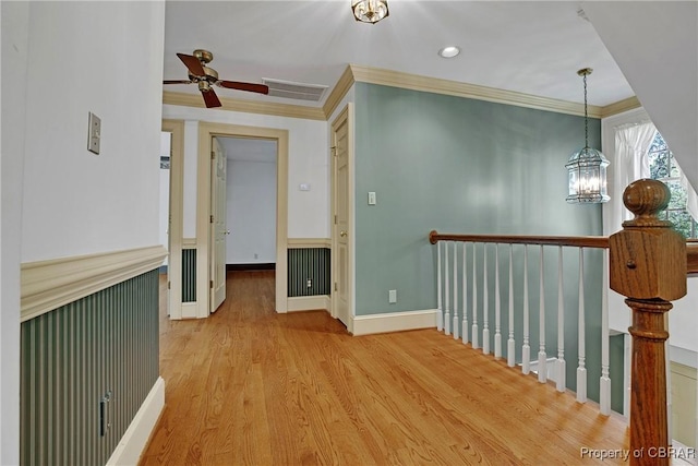 corridor featuring wood finished floors, visible vents, ornamental molding, an upstairs landing, and a chandelier