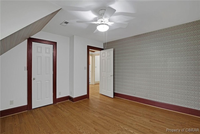 unfurnished bedroom featuring baseboards, a ceiling fan, visible vents, and light wood-style flooring
