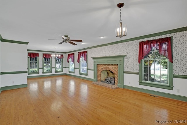 unfurnished living room featuring a fireplace, wallpapered walls, visible vents, and crown molding