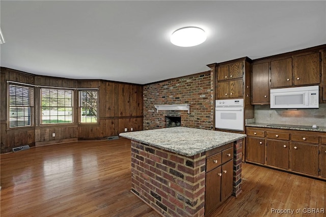kitchen featuring wood finished floors, a center island, open floor plan, and white appliances