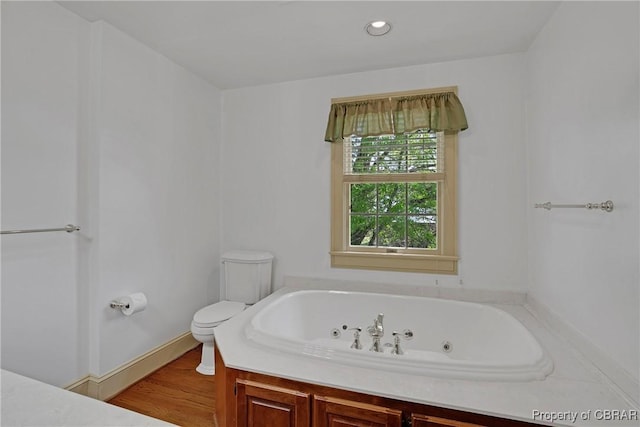 bathroom featuring wood finished floors, a jetted tub, recessed lighting, and toilet