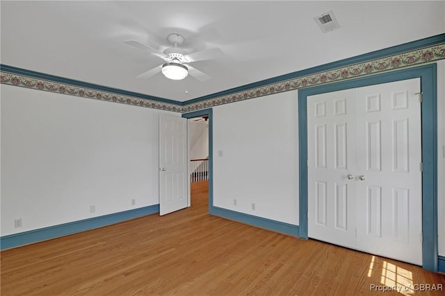 unfurnished bedroom with a closet, light wood-style floors, ceiling fan, baseboards, and visible vents
