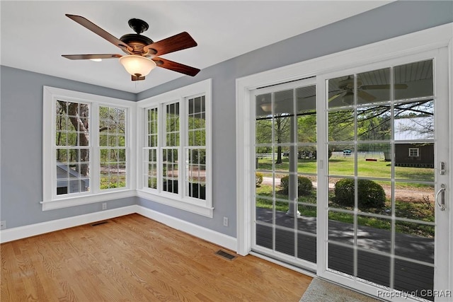 interior space featuring visible vents, wood finished floors, baseboards, and ceiling fan
