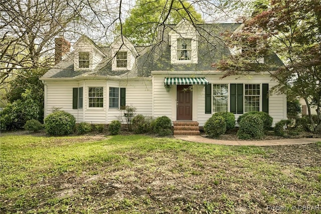 new england style home featuring a chimney and a front lawn