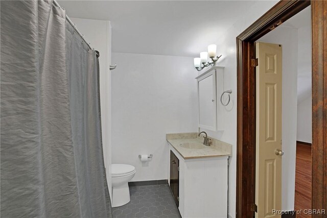 full bathroom with baseboards, toilet, vanity, and tile patterned floors