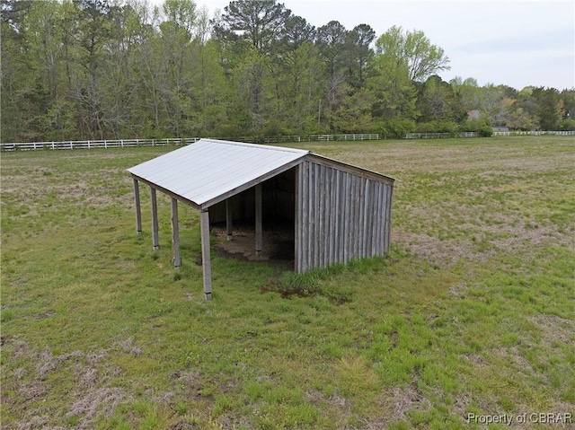 view of pole building with fence, a yard, a wooded view, and a detached carport