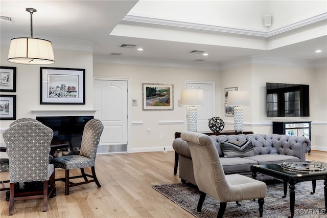 living room featuring a fireplace, baseboards, ornamental molding, recessed lighting, and light wood-style flooring