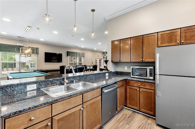 kitchen featuring crown molding, pendant lighting, a sink, light wood-style flooring, and appliances with stainless steel finishes