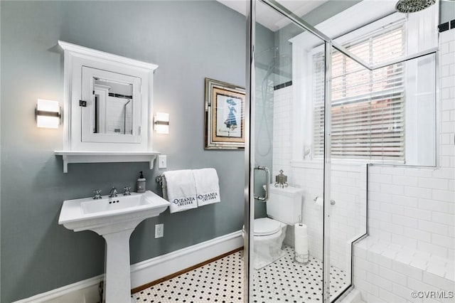 bathroom with toilet, baseboards, and a stall shower
