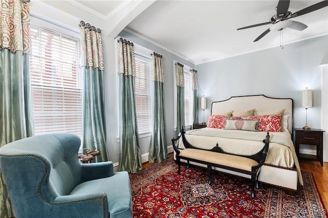bedroom featuring crown molding, arched walkways, a ceiling fan, and wood finished floors