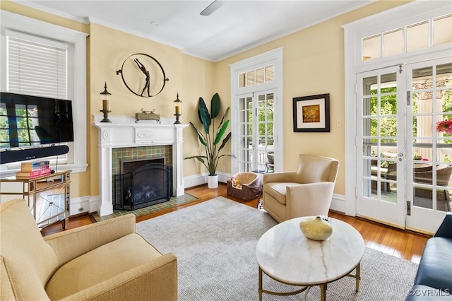 living room with a tiled fireplace, crown molding, french doors, and wood finished floors
