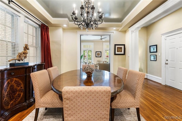 dining room featuring baseboards, decorative columns, ceiling fan with notable chandelier, and wood finished floors