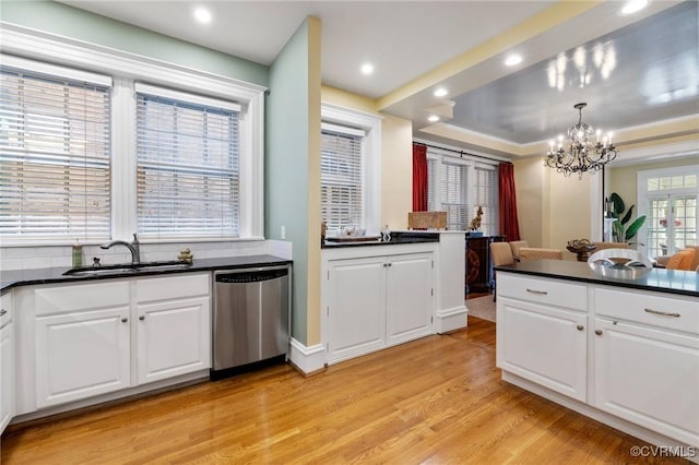 kitchen with dark countertops, stainless steel dishwasher, a sink, a chandelier, and light wood-style floors