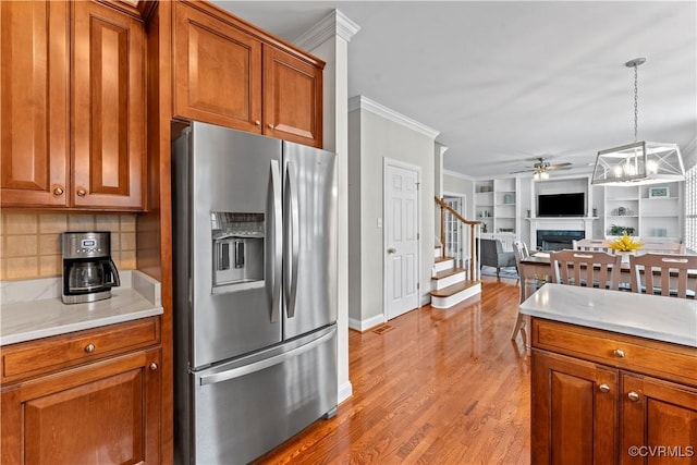 8500 Baldwin Creek Rd, Chesterfield, VA 23832 - kitchen featuring brown cabinetry, ornamental molding, a fireplace, ceiling fan, and stainless steel refrigerator with ice dispenser