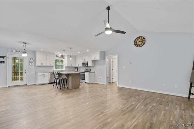 living room with ceiling fan, vaulted ceiling, baseboards, and light wood finished floors