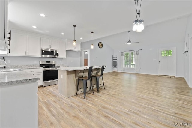 kitchen with white cabinets, a sink, stainless steel appliances, a ceiling fan, and a kitchen island