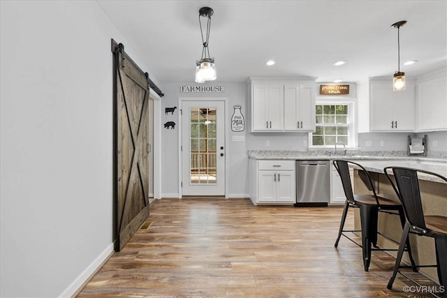kitchen with stainless steel dishwasher, white cabinets, light stone countertops, and a barn door