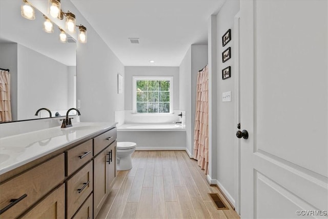 bathroom featuring double vanity, visible vents, wood finished floors, a sink, and toilet