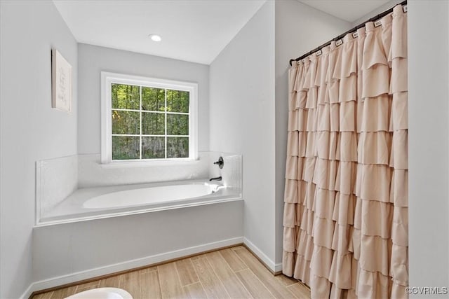 full bathroom with a shower with curtain, baseboards, a garden tub, and wood finished floors